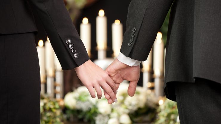 Hände eines Paares halten sich, umgeben von Kerzen und Blumenarrangements, in festlicher Atmosphäre.