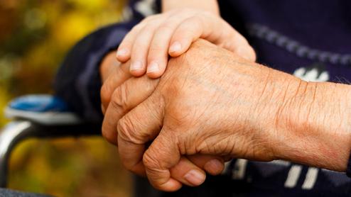 Nahaufnahme zweier Hände, eine ältere und eine jüngere, die sich miteinander halten. Hintergrund unscharf.